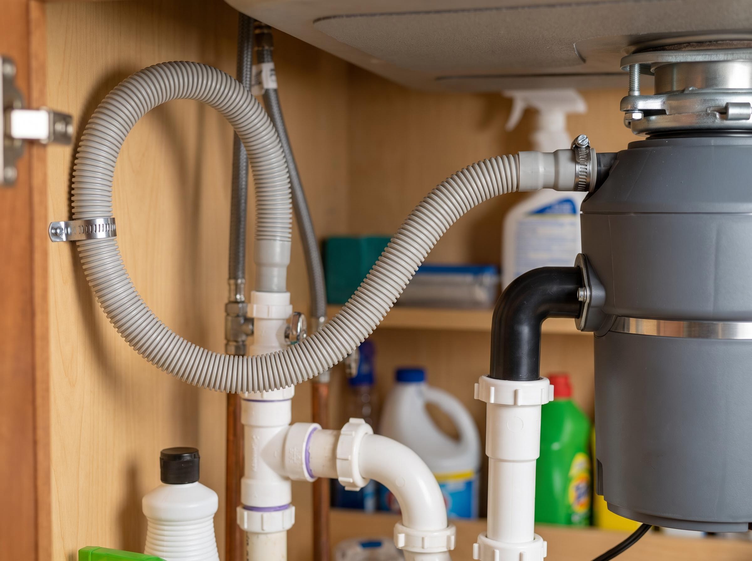 Under-sink dishwasher drain hose on a high loop into the disposal inlet.